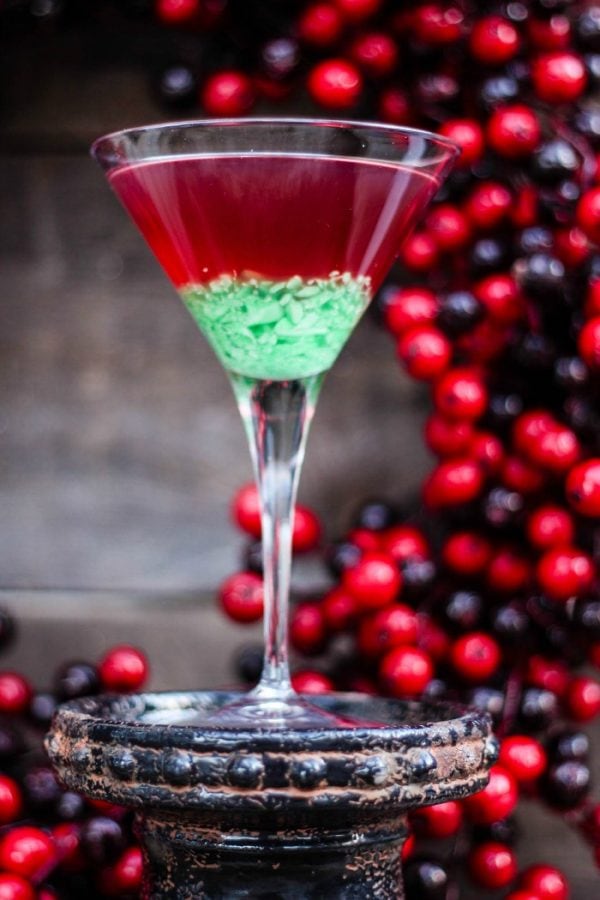 Red and green martini next to holiday decor. 