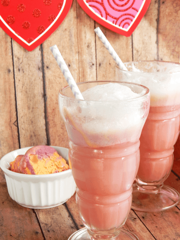 Two glasses of pink punch next to a cup of sherbet