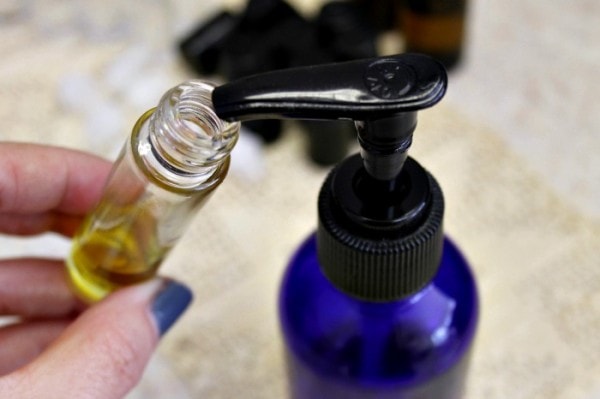 Holding a roller bottle up to a pump. 