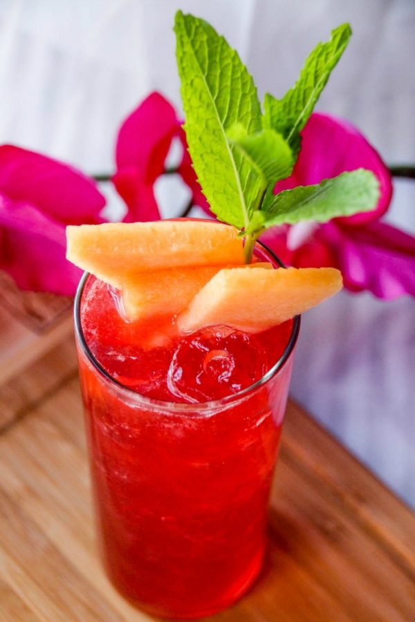 Raspberry cocktail with cantaloupe slices in it. 