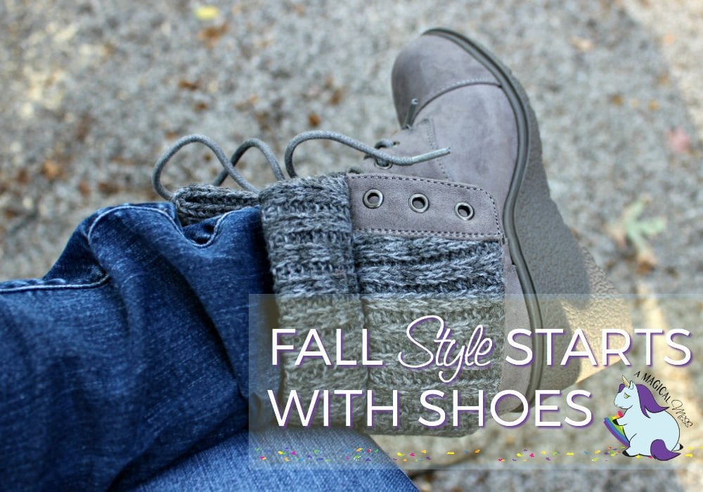 Gray boots on a foot of person wearing jeans. 