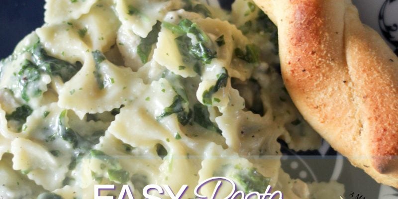 Pasta dinner on a plate with a breadstick. 