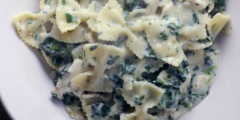 Bowl of bow-tie pasta and a spinach cream sauce. 