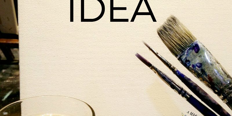 A canvas with paintbrushes next to a beer. 