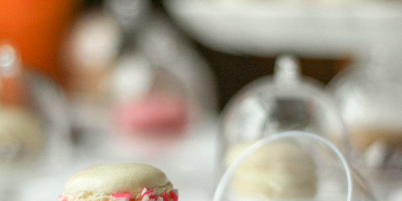 A mini macaron on a cake stand with the lid off. 