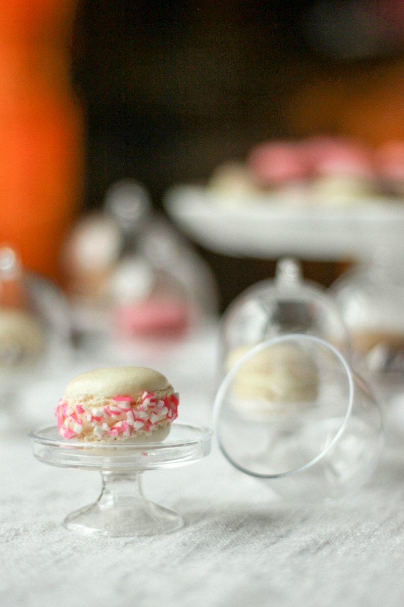 A mini macaron on a cake stand with the lid off.