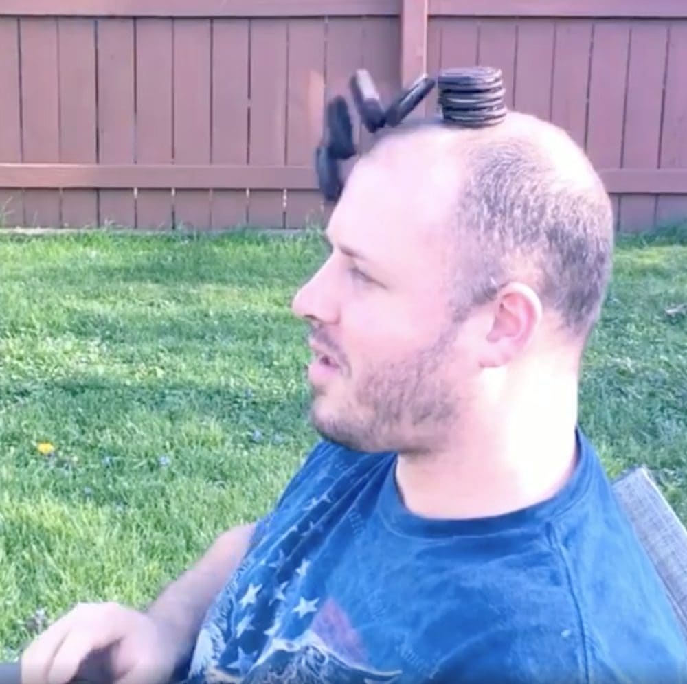 Man sitting with a stack of OREOS on his head which are falling over.