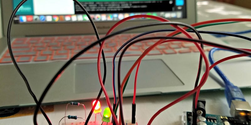 Pressing the button on a circuit board with a lap top in the background.