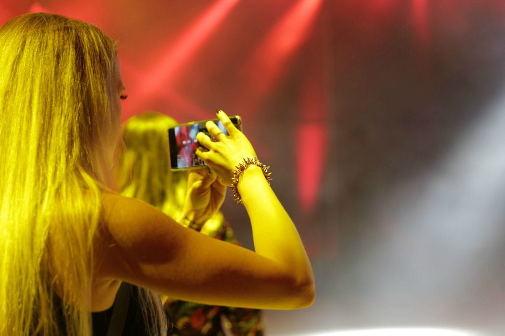 Shelley taking a picture with a cell phone at an event.
