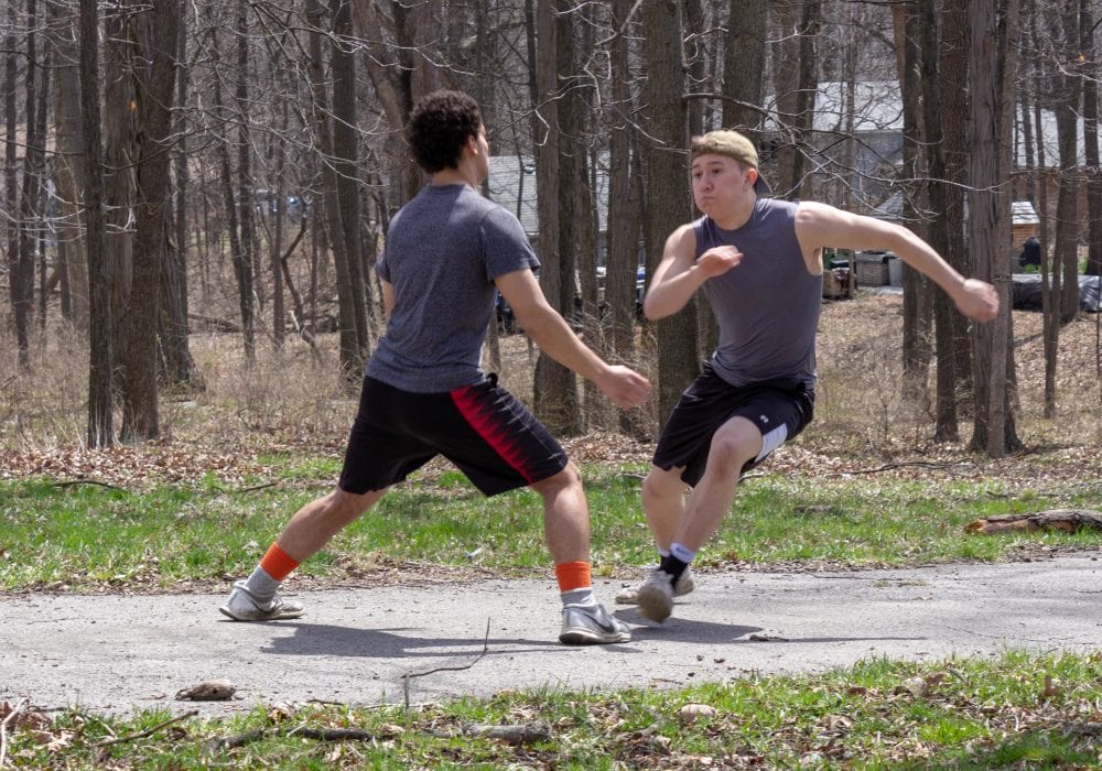 Two males running on a driveway. 