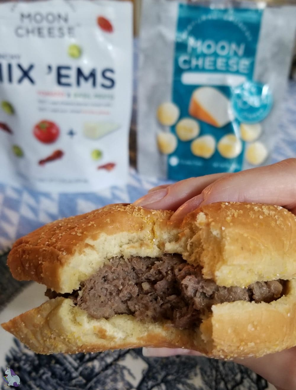 Holding a burger with a bite taken out of it. 