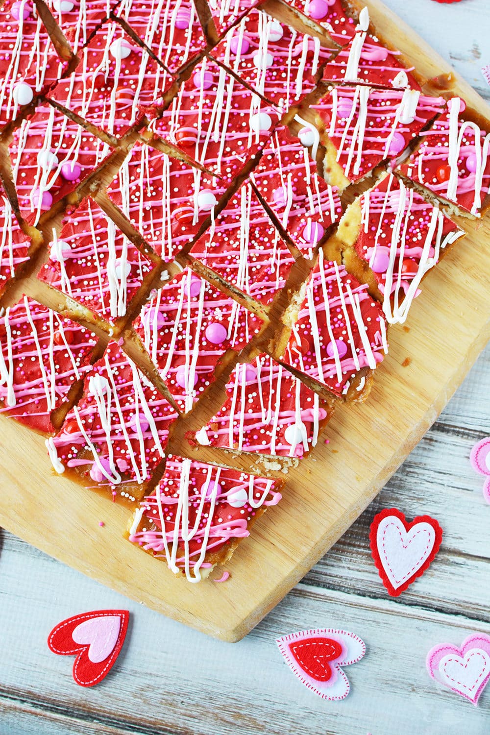Cracker candy with red, white, and pink chocolates on a cutting board.