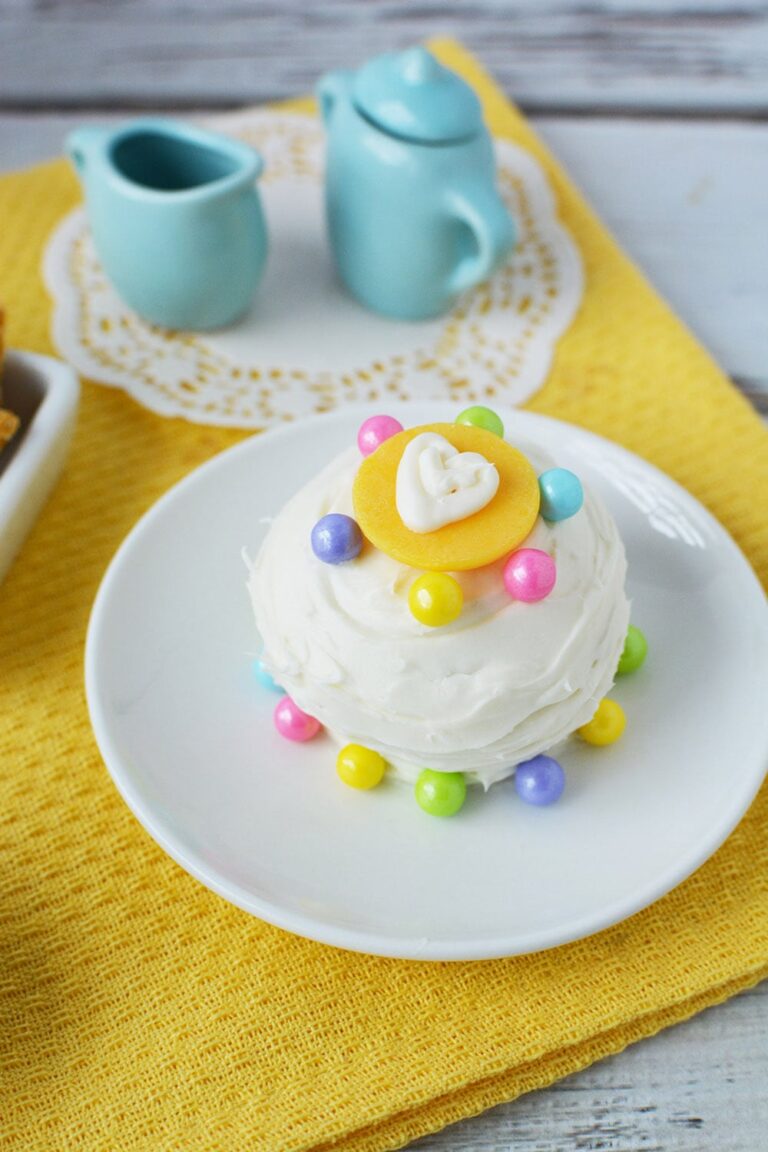 White mini cake on a plate with blue tea set.
