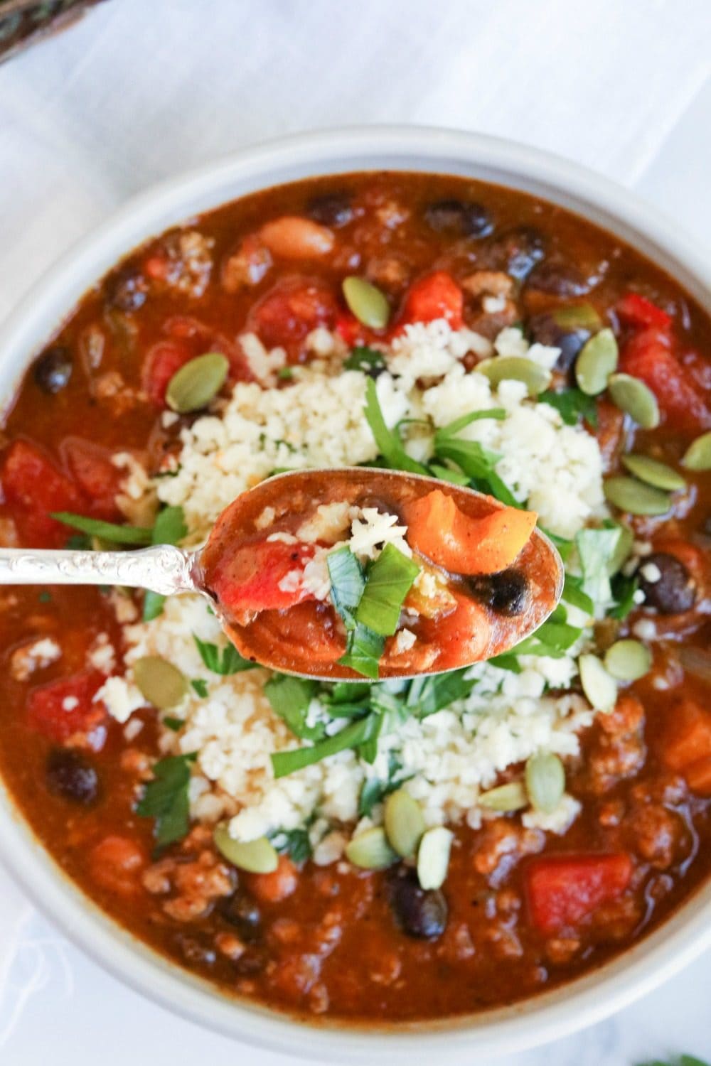 Overhead shot of a spoonful of pumpkin chili over the bowl. 