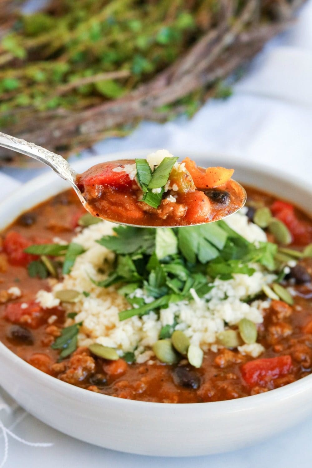Spoonful of chili over a bowl. 