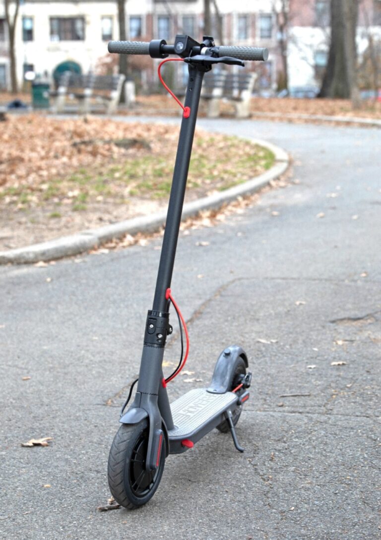 Scooter in the street with leaves in the background.