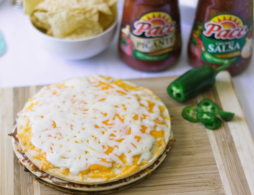 Double decker taco pizza with pace sauce in the background. 