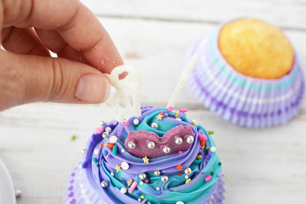 Putting candy wings on a cupcake.