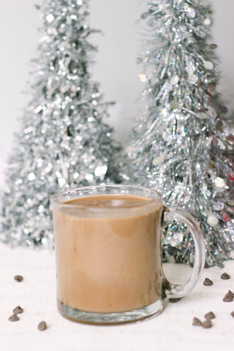 Glass of low car hot chocolate in front of silver Christmas trees