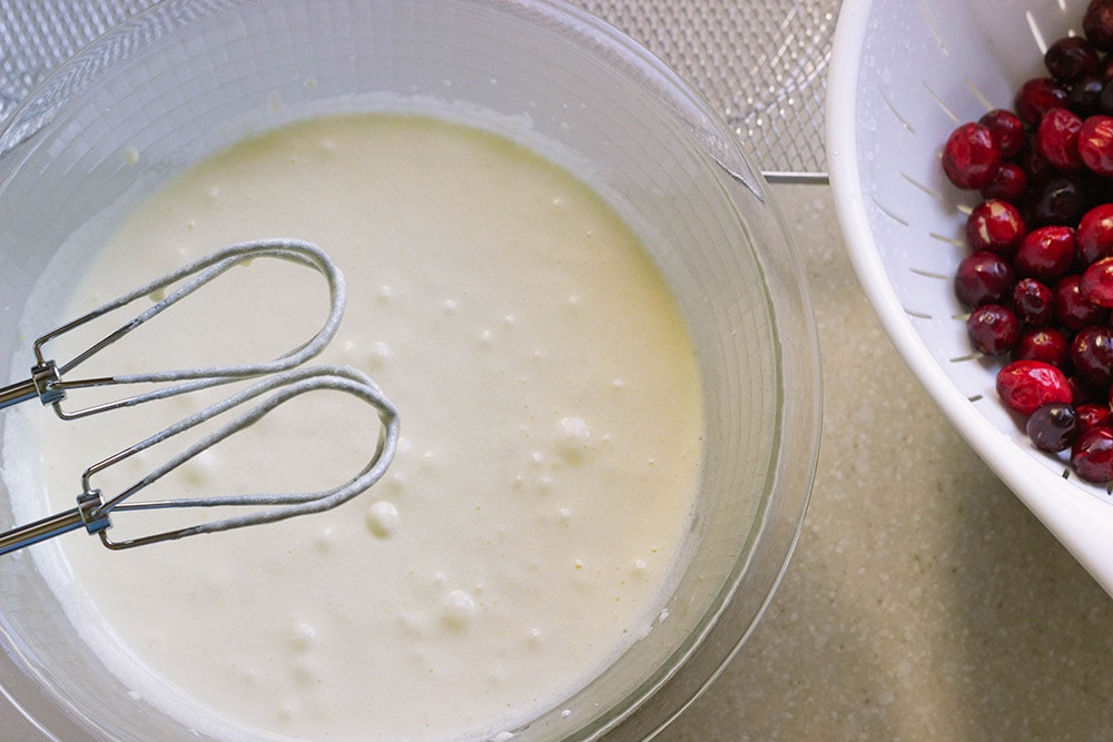 Cake batter in a bowl with the mixer above it. 