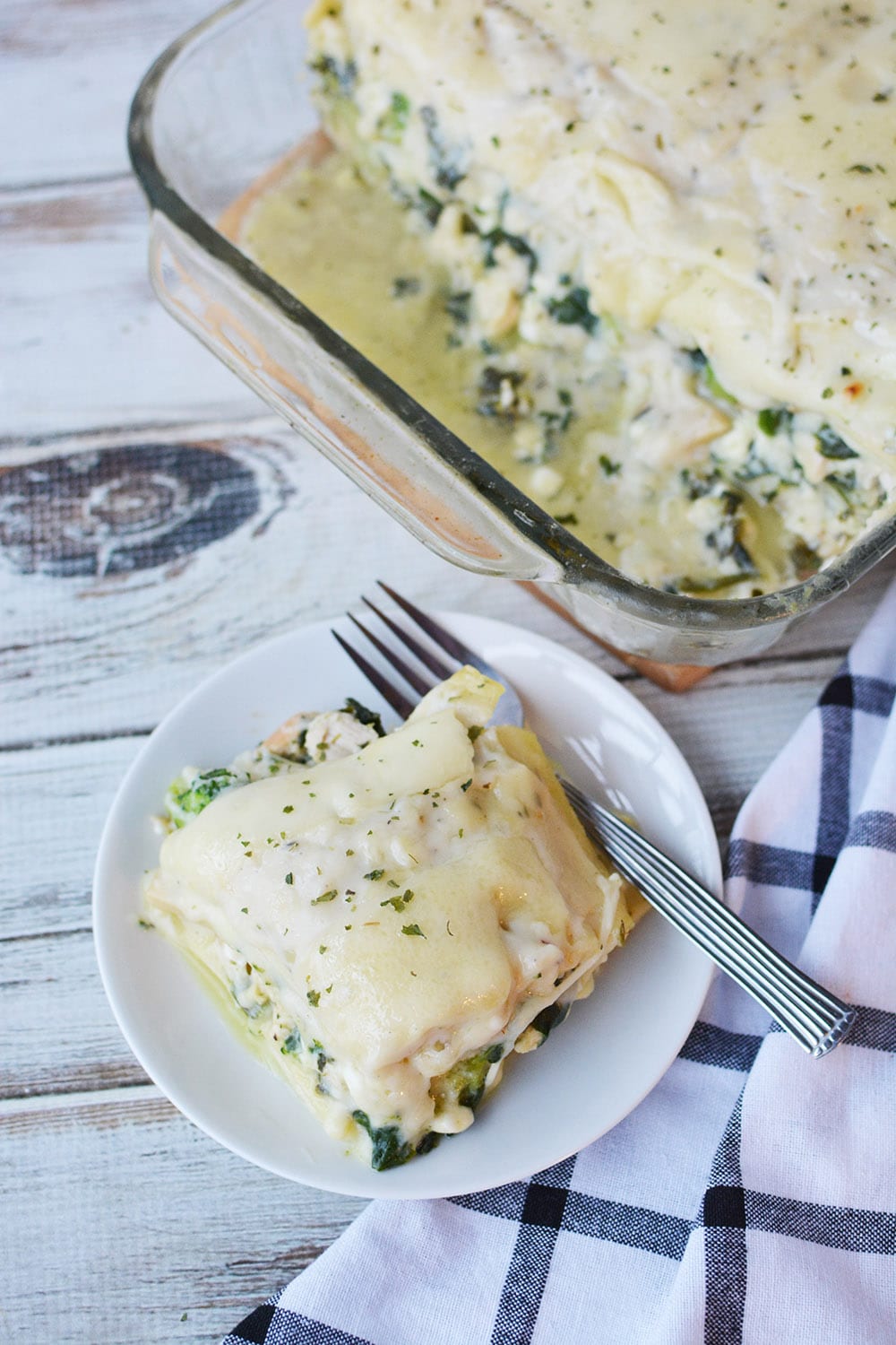 Overhead image of spinach lasagna with chicken on a plate and in the baking dish. 