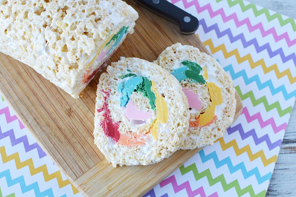 Slice of pinwheel rice crispy treats on a rainbow chevron background.