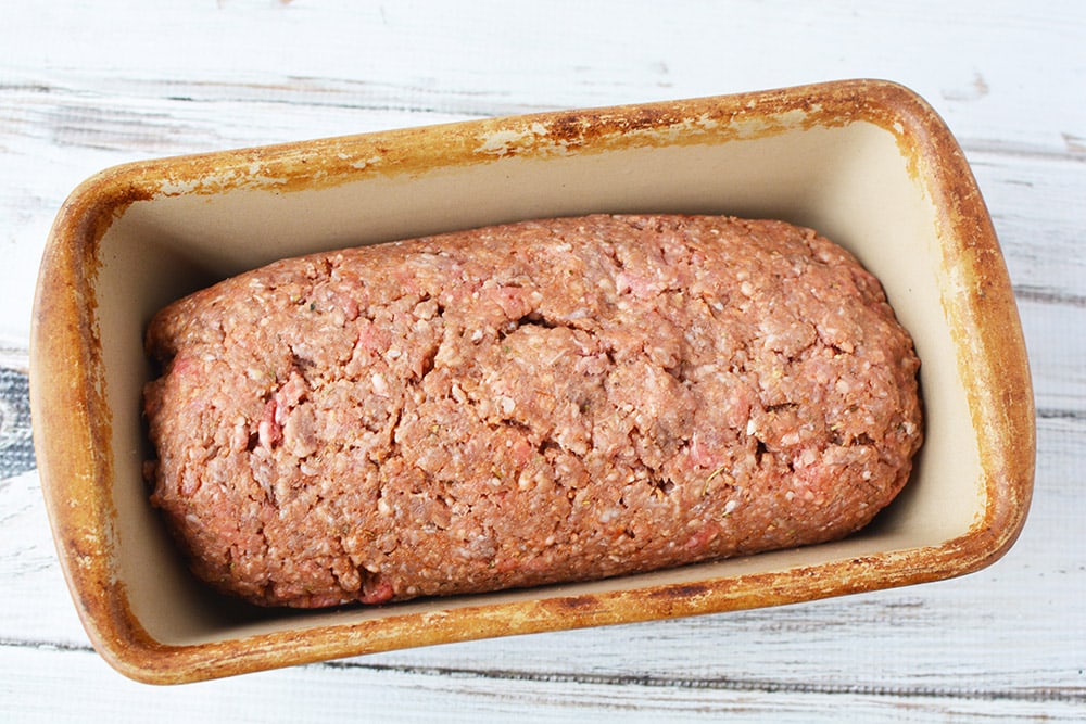 Cheese stuffed meatloaf in a loaf pan ready for the oven.