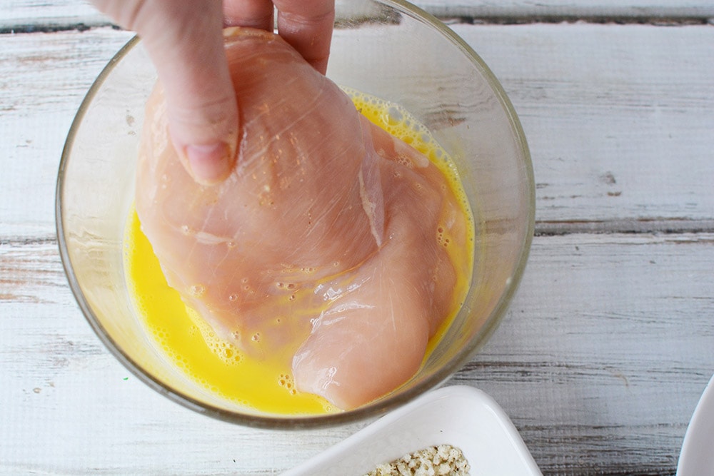 Dipping raw chicken in to egg.