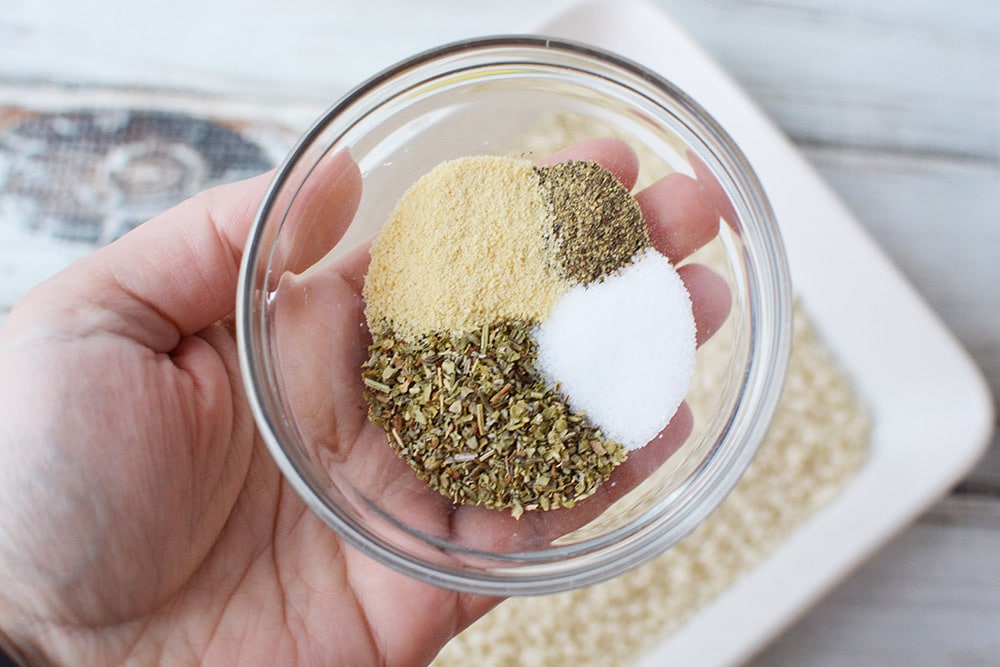 Holding seasonings in a bowl above bread crumbs.