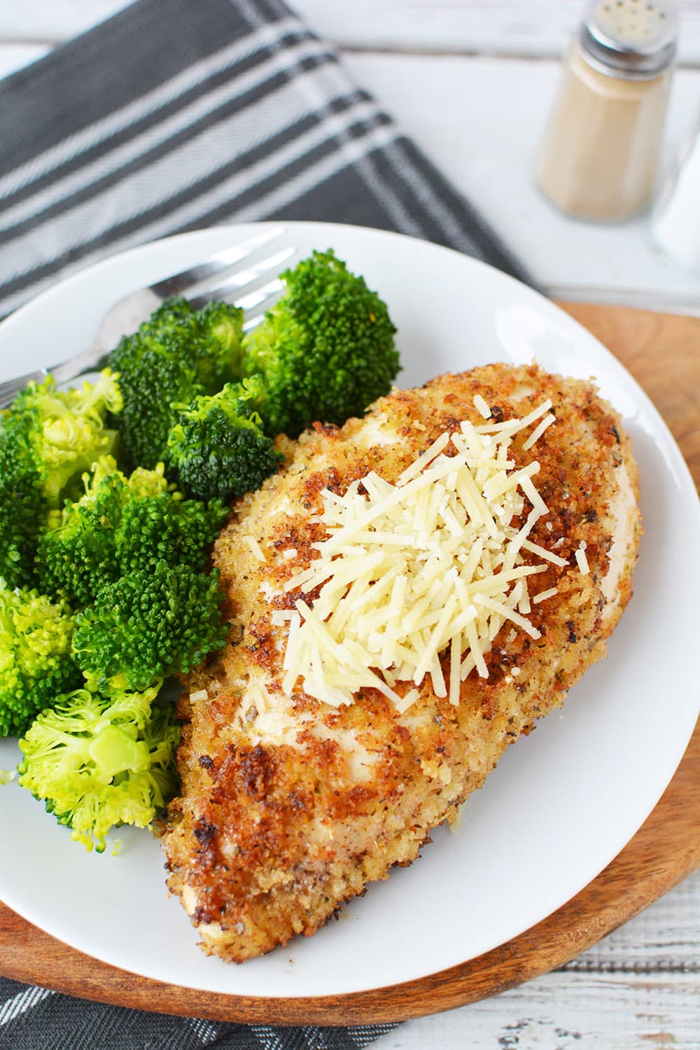 Plate of crispy chicken topped with parmesan and broccoli.