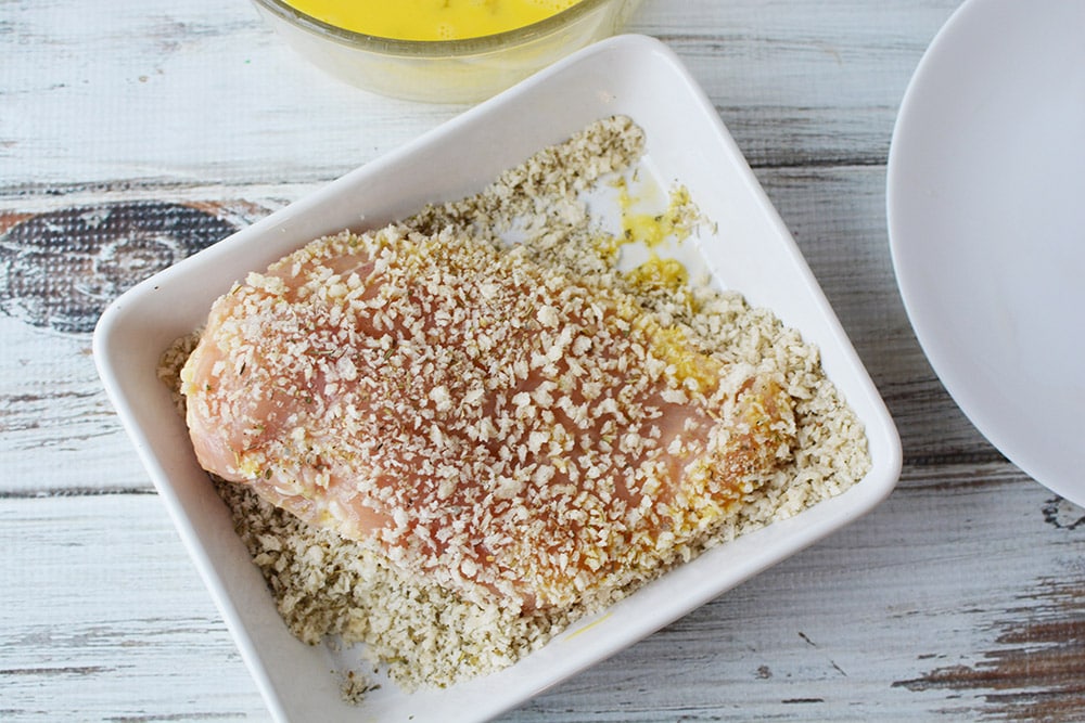 Chicken coated with bread crumbs in a dish.