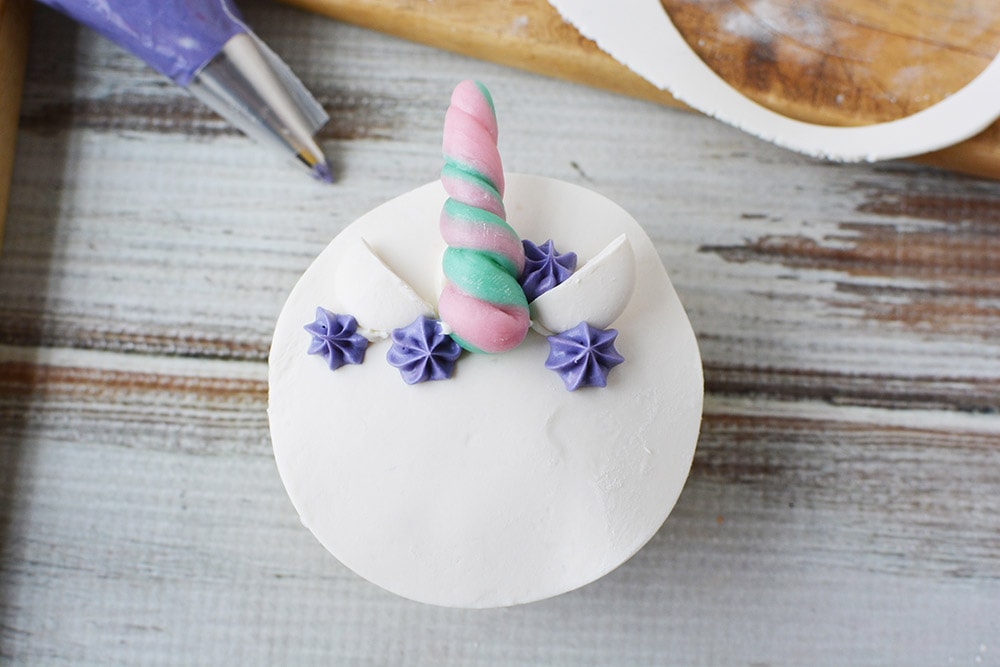 Decorating a unicorn cupcake with purple frosting.