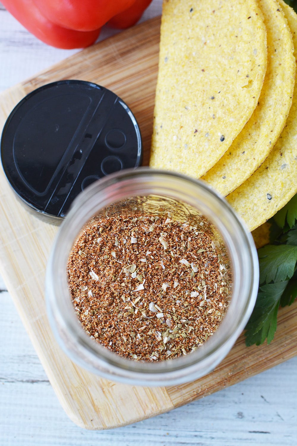 Overhead shot of taco seasoning mix in a jar next to taco shells. 