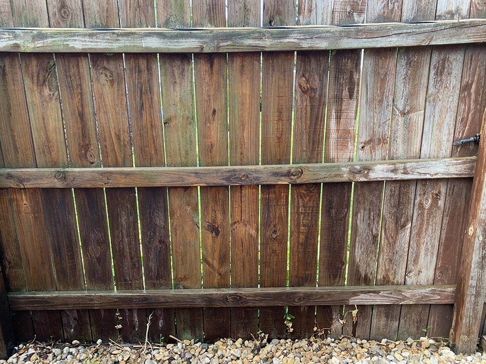 A fence with one side power washed and one before.