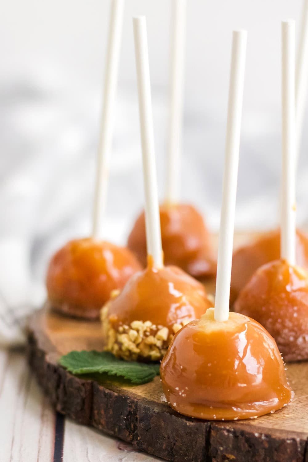 Caramel apple bites with sticks on a board.