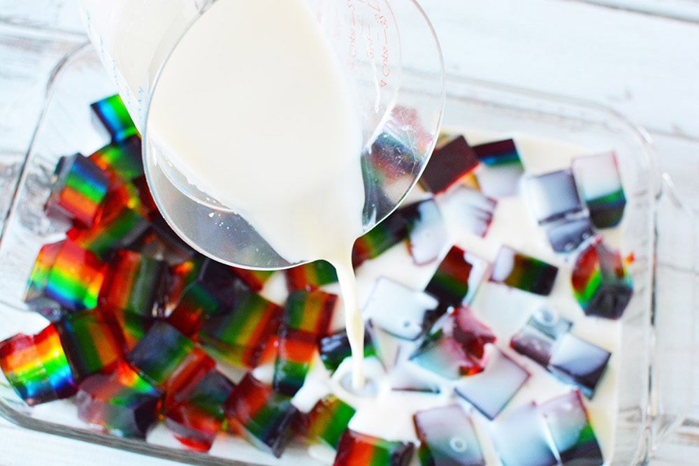 Pouring condensed milk over jello.