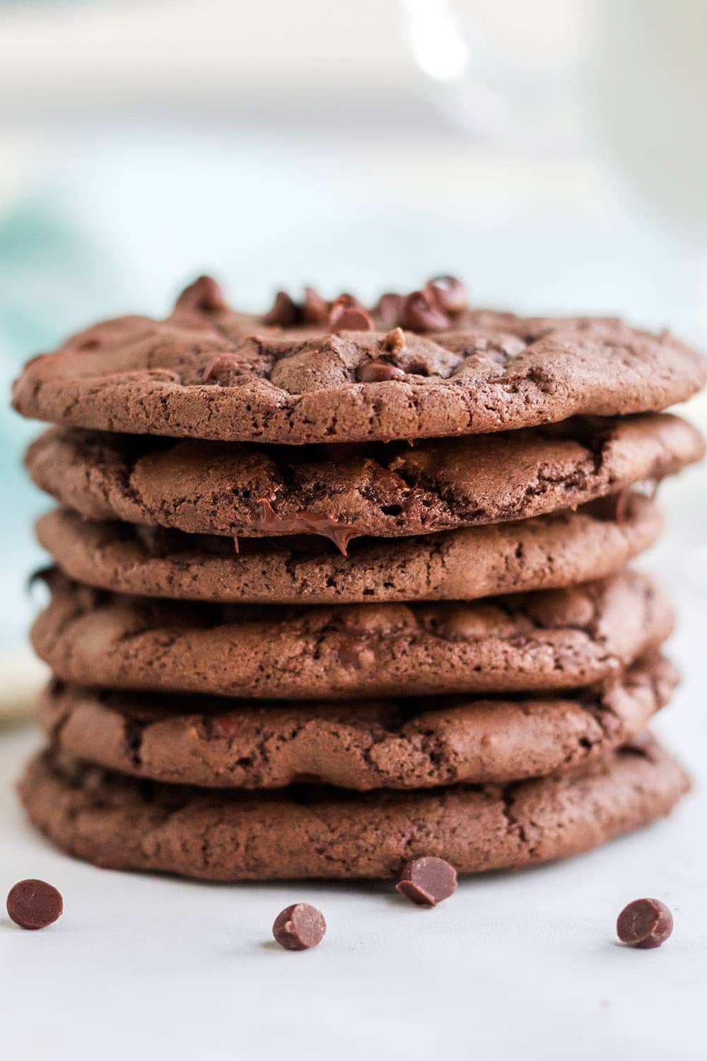 Stack of brownie cookies with chocolate chips on a white table with a blue napkin.