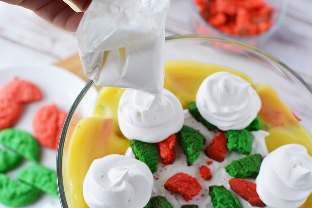 Piping whipped topping onto Christmas trifle.
