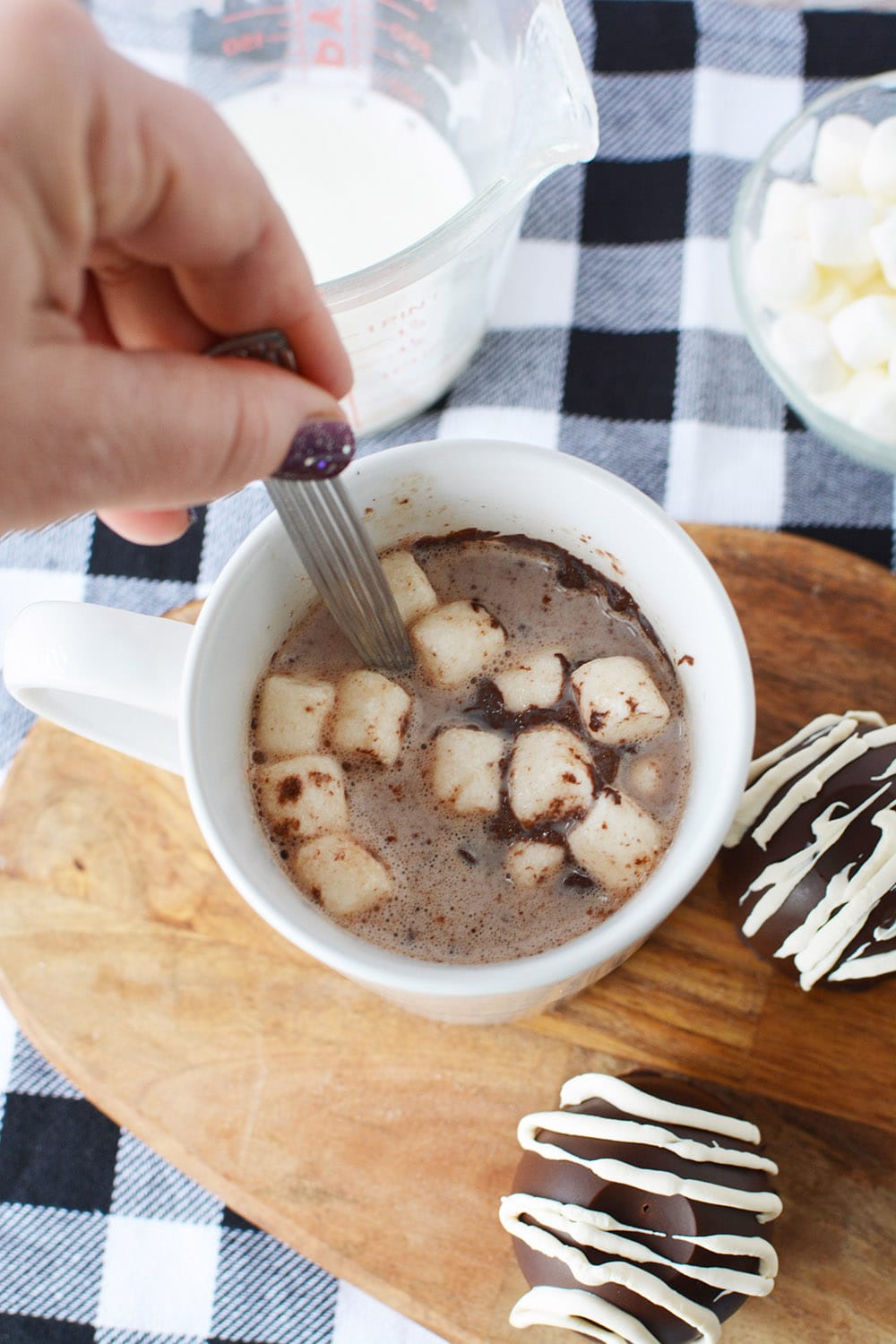 Stirring hot chocolate with marshmallows in a mug.