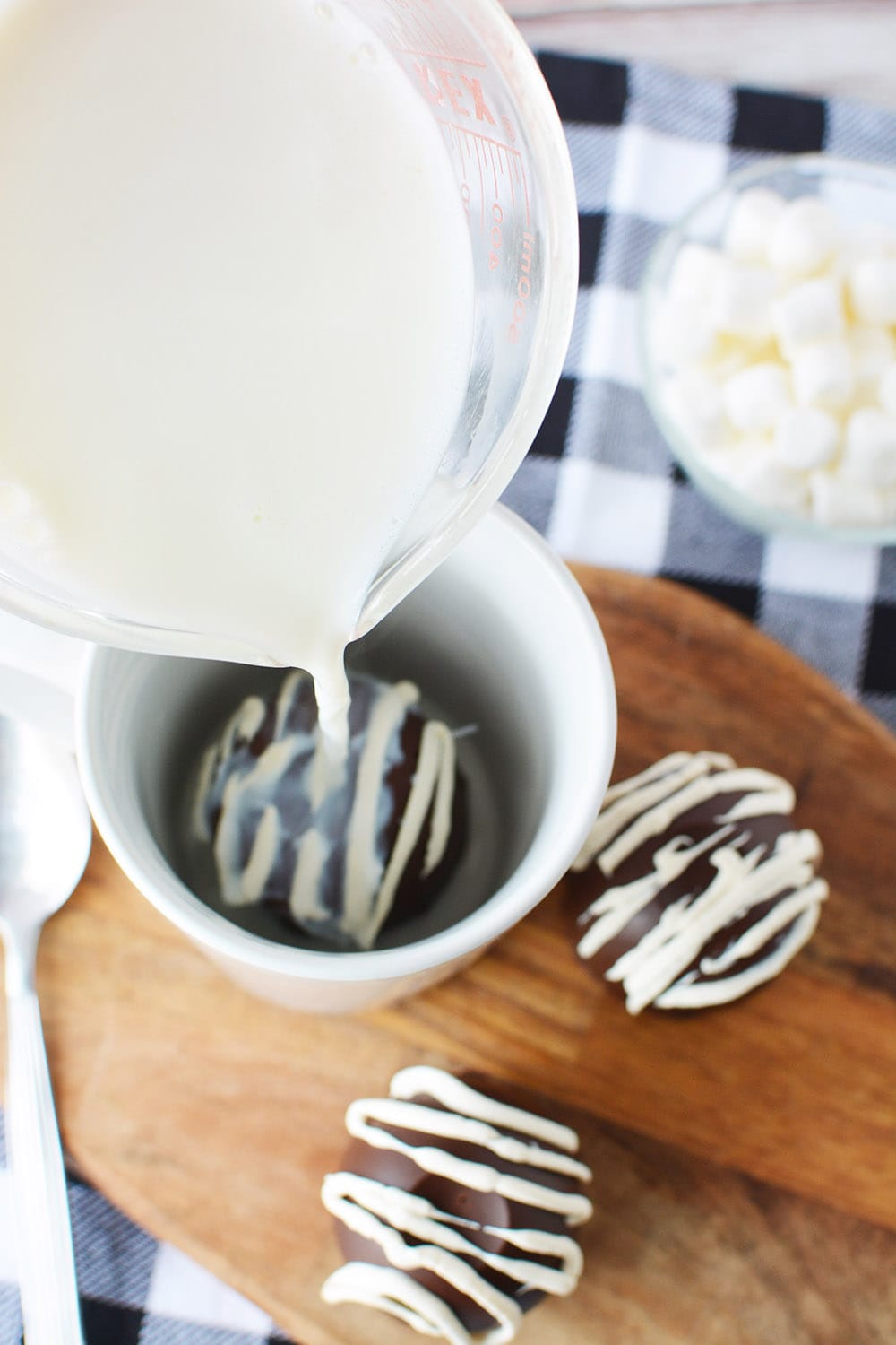 Pouring hot milk onto a hot cocoa bomb in a mug.