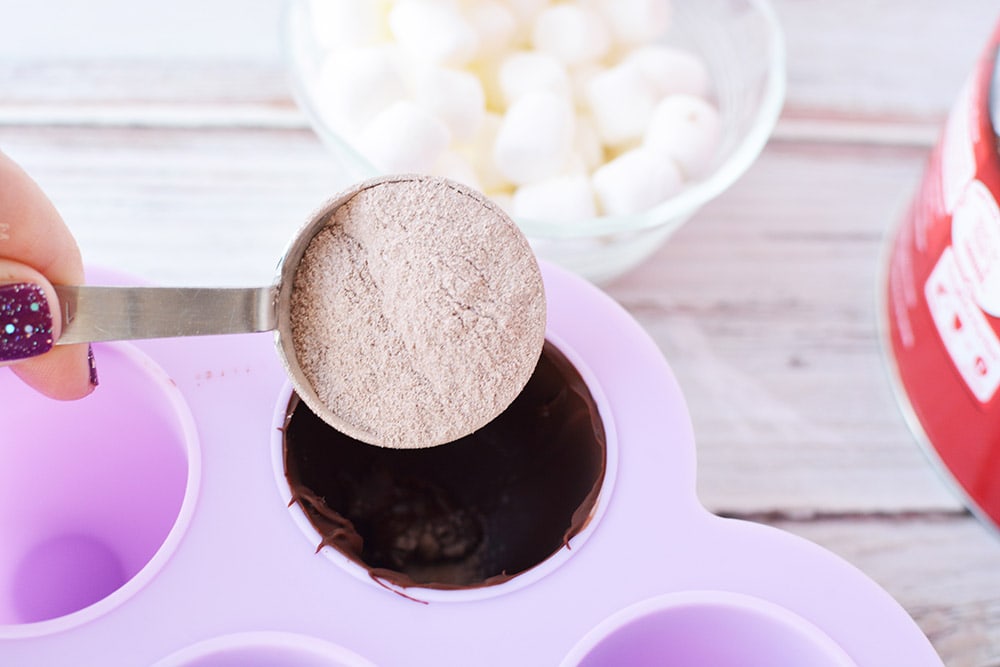 Pouring a scoop of hot chocolate into a candy mold.