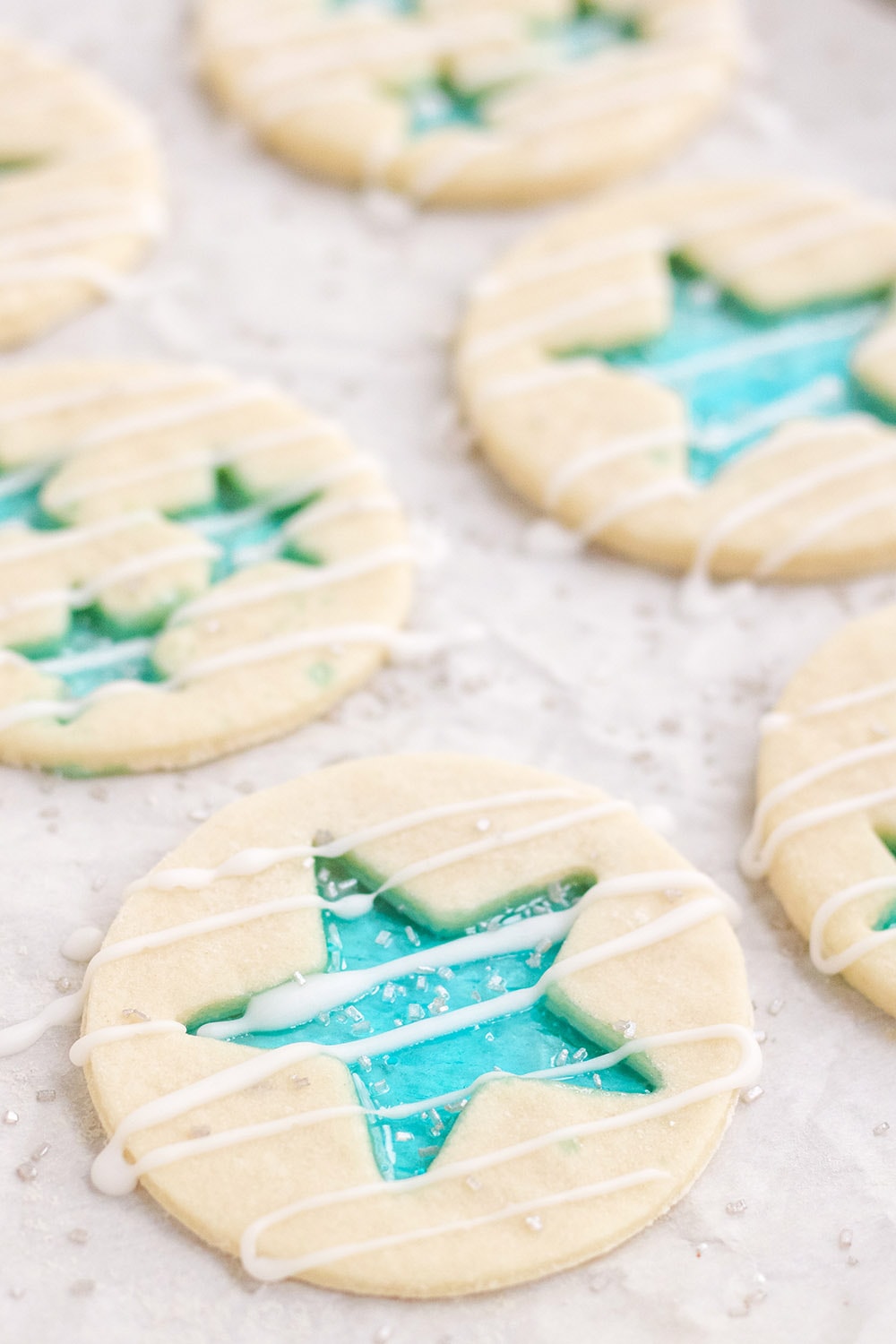 Glaze drizzled onto star candy cookies on a baking sheet. 