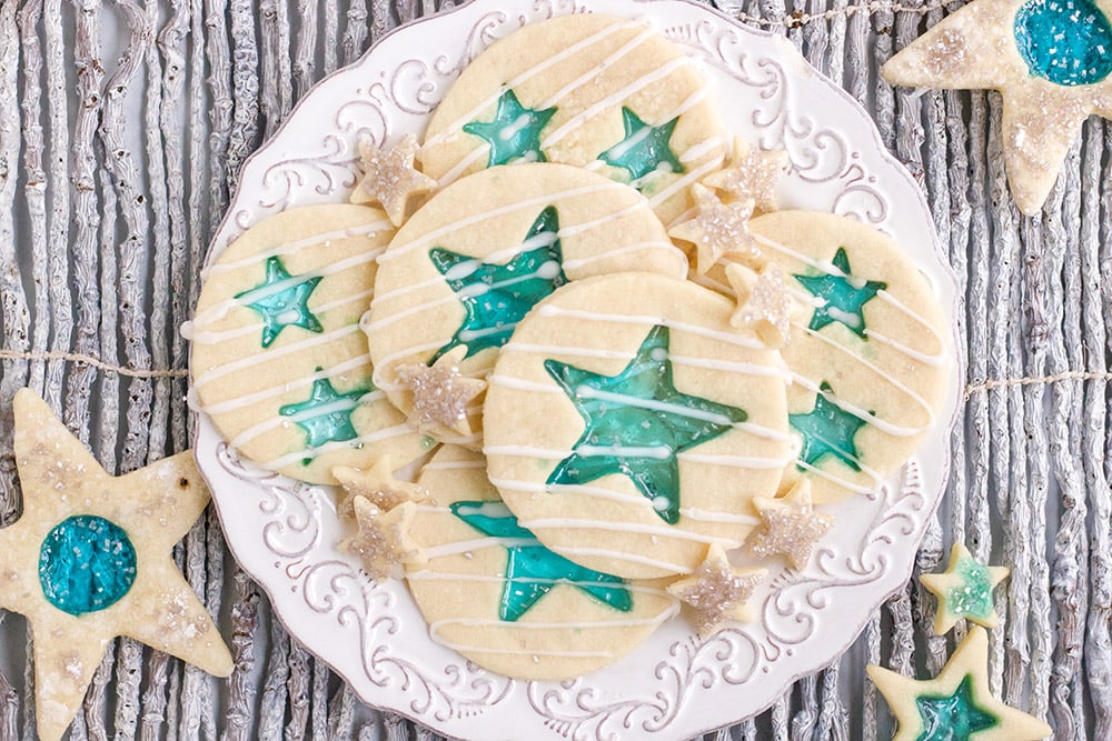 Stained-glass cookies with blue stars on a white plate on a gray table. 