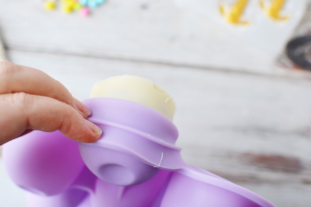 Popping white hot chocolate bomb out of candy mold.