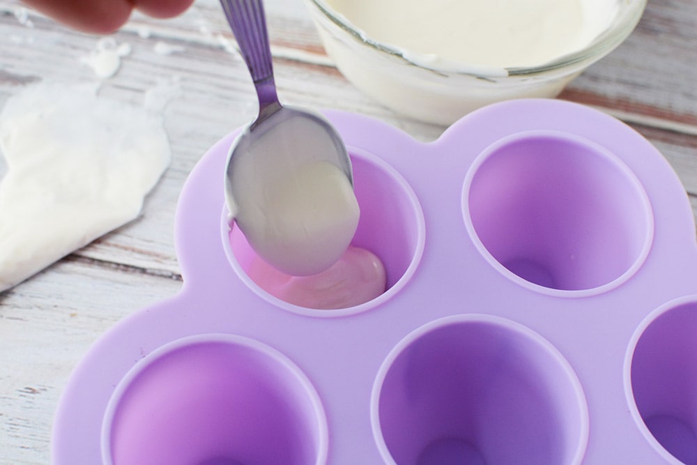 Spooning melted white chocolate into mold.