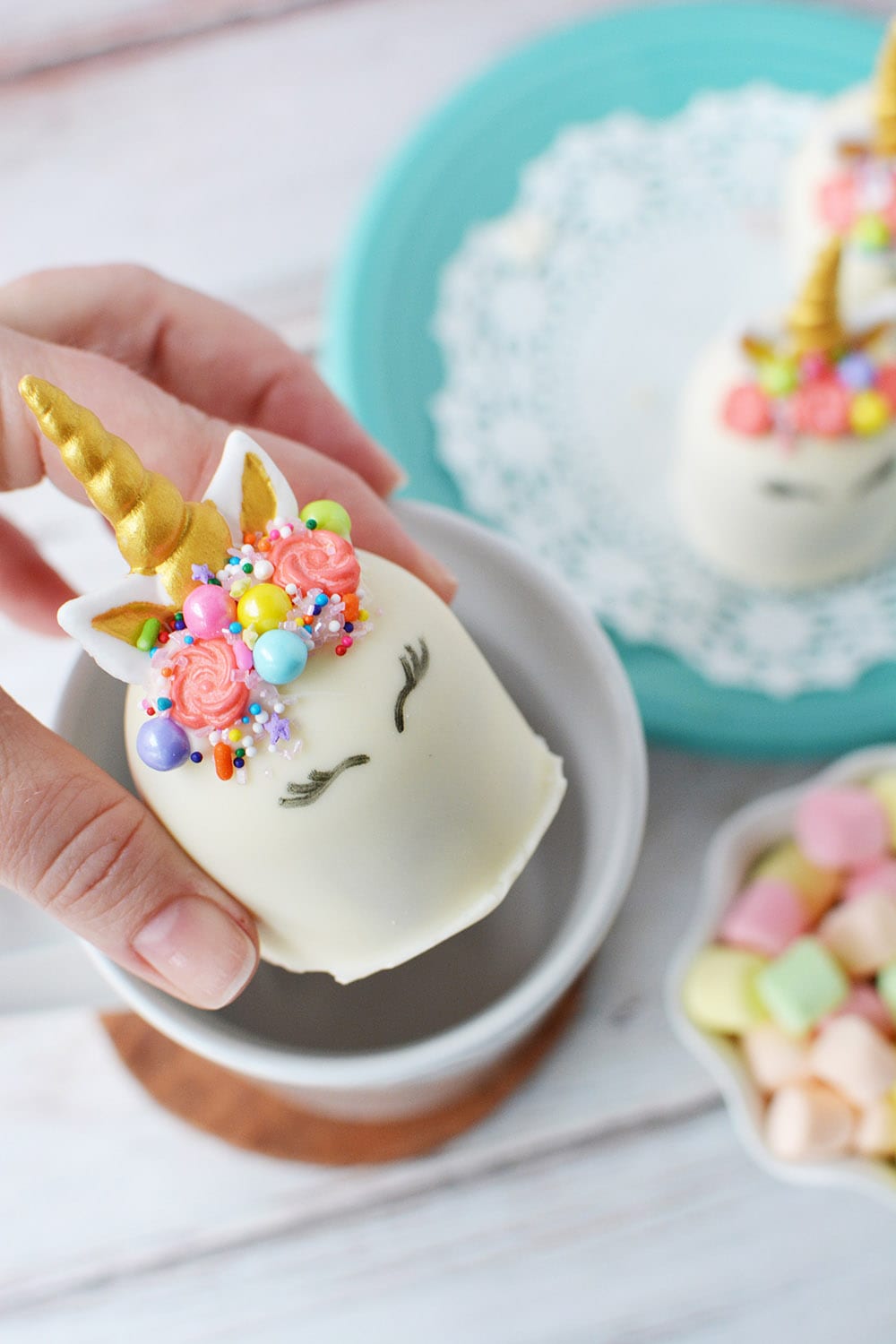 Putting a unicorn hot chocolate bomb into a mug.