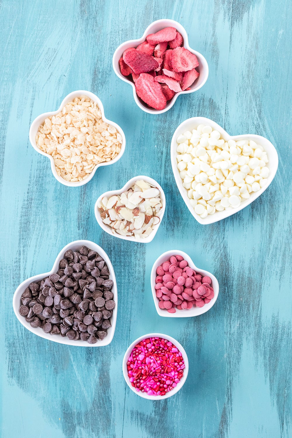 Bowls with ingredients for bark candy on a blue table.
