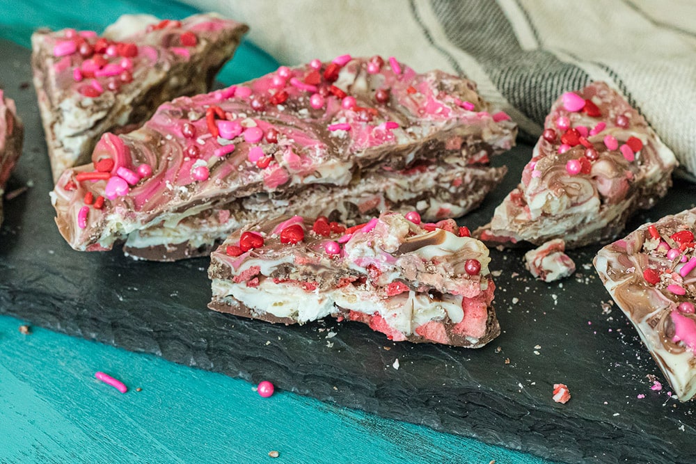 Candy with sprinkles broken into pieces lined up on a board.