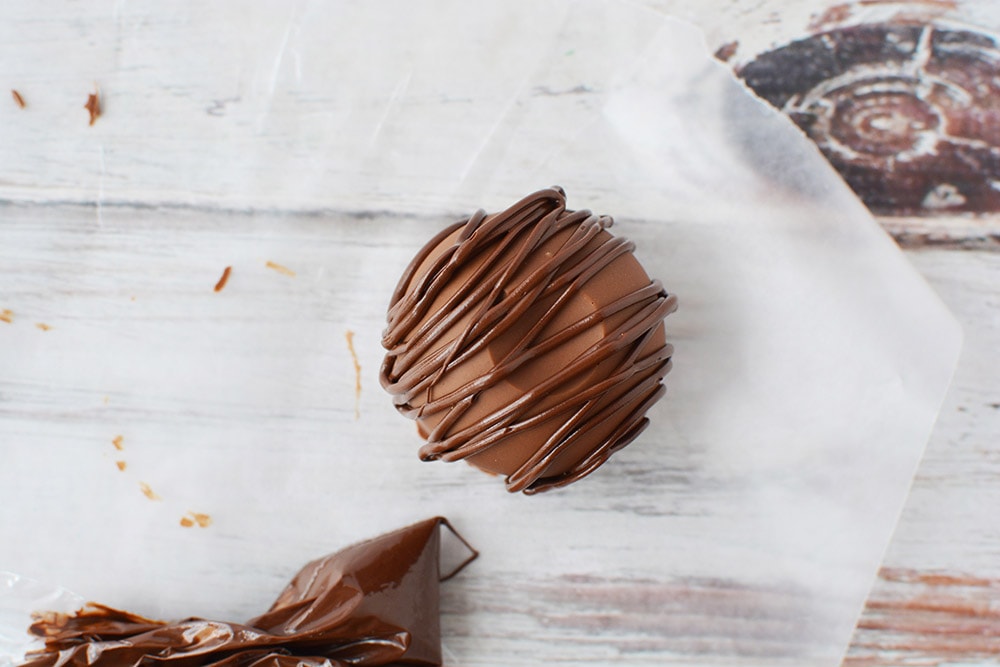 Drizzling dark chocolate over a mocha coffee bomb.