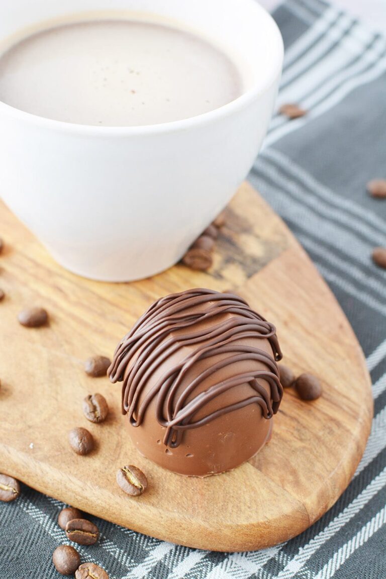 Mocha coffee bomb candy sitting next to a mug full of coffee.